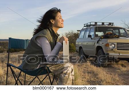 Stock Photo - Hispanic woman holding laptop outdoors. Fotosearch