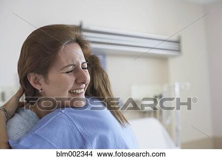 Picture - Hispanic woman hugging medical professional. Fotosearch