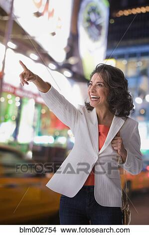 Hispanic woman in city smiling and pointing View Large Photo Image Picture - Hispanic woman in city smiling and pointing. Fotosearch