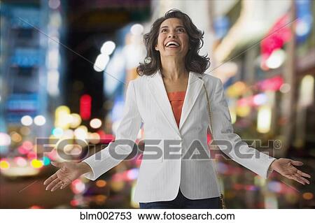 Stock Image - Hispanic woman in city smiling and looking up. Fotosearch