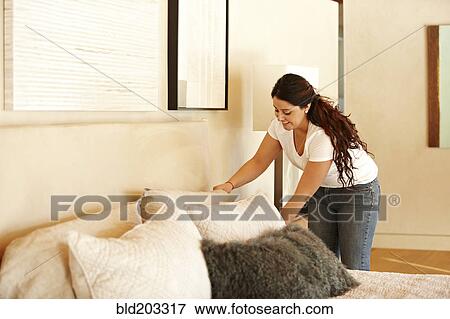Stock Photo - Hispanic woman making bed. Fotosearch