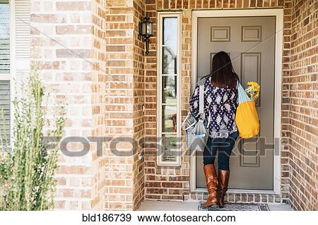 Stock Photo - Hispanic woman opening front door. Fotosearch