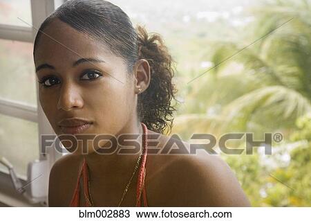 Stock Image - Hispanic woman sitting near window. Fotosearch