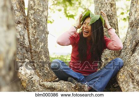 Hispanic woman sitting outdoors with leaf on her head View Large Photo Image Stock Photograph - Hispanic woman sitting outdoors with leaf on her head. Fotosearch