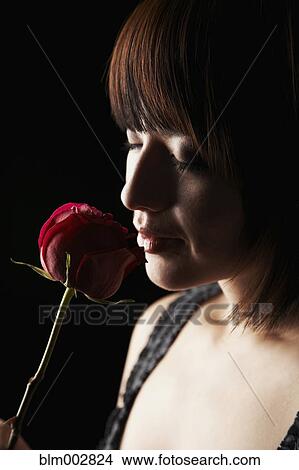 Picture - Hispanic woman smelling flower. Fotosearch