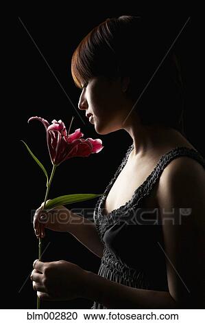 Stock Image - Hispanic woman smelling flower. Fotosearch
