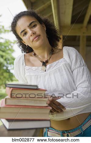 Stock Photo - Hispanic woman standing with textbooks. Fotosearch