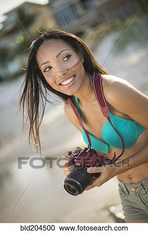 Stock Image - Hispanic woman taking pictures outdoors. Fotosearch