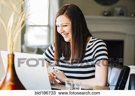 Stock Image - Hispanic woman using laptop. Fotosearch