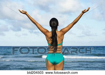 Stock Image - Hispanic woman wearing bikini on beach. Fotosearch