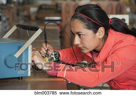 Stock Photography - Hispanic woman working in electronics lab. Fotosearch