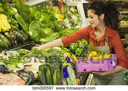 Stock Photo - Hispanic woman working in produce section of grocery store. Fotosearch