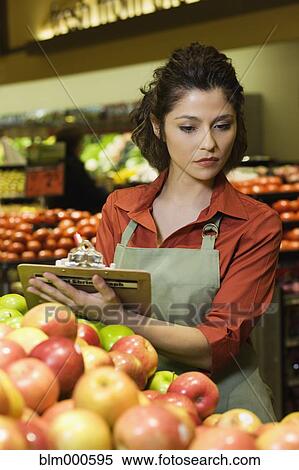 Stock Photography - Hispanic woman working in produce section of grocery store. Fotosearch