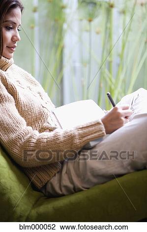 Stock Image - Hispanic woman writing in journal. Fotosearch