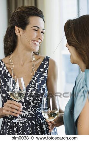 Stock Image - Hispanic women drinking white wine. Fotosearch