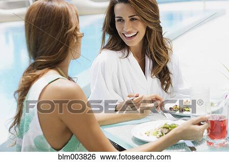 Stock Photograph - Hispanic women eating lunch poolside. Fotosearch