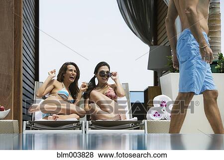 Stock Photo - Hispanic women in bikinis eyeing passing man. Fotosearch