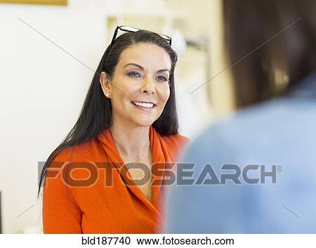 Stock Image - Hispanic women talking indoors. Fotosearch