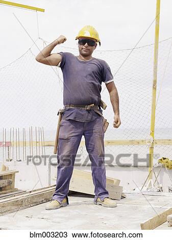 Hispanic worker flexing biceps on construction site View Large Photo Image Stock Image - Hispanic worker flexing biceps on construction site. Fotosearch