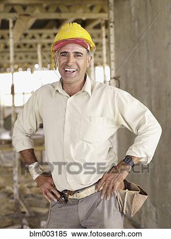 Stock Photography - Hispanic worker smiling at construction site. Fotosearch