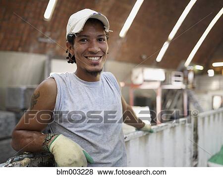 Stock Photo - Hispanic worker smiling in factory. Fotosearch