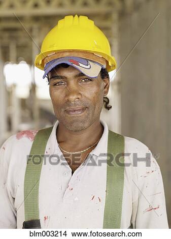Picture - Hispanic worker smiling on construction site. Fotosearch
