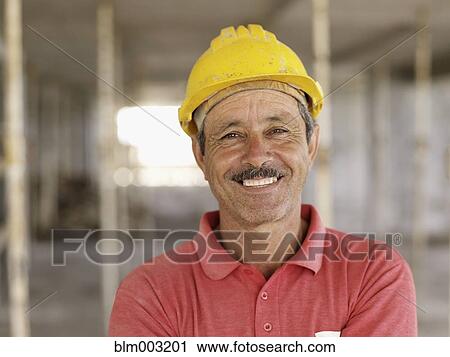 Stock Image - Hispanic worker smiling on construction site. Fotosearch