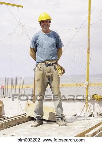 Stock Image - Hispanic worker smiling on construction site. Fotosearch