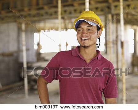 Hispanic worker smiling on construction site View Large Photo Image Stock Photo - Hispanic worker smiling on construction site. Fotosearch