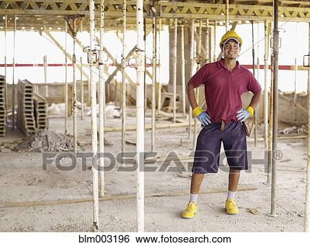 Hispanic worker standing on construction site View Large Photo Image Stock Photograph - Hispanic worker standing on construction site. Fotosearch