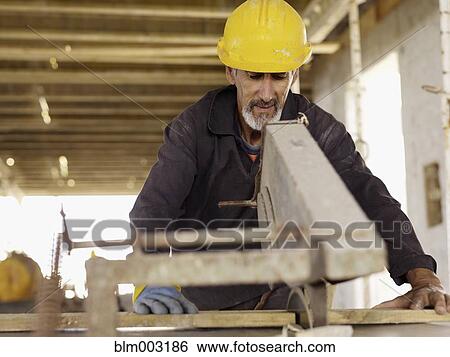 Stock Photograph - Hispanic worker using saw at construction site. Fotosearch