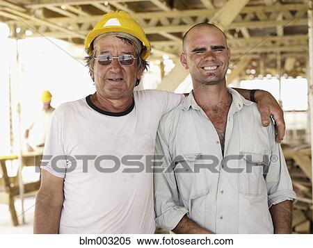 Stock Photography - Hispanic workers hugging construction site. Fotosearch