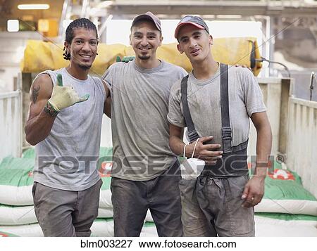 Stock Photo - Hispanic workers hugging in factory. Fotosearch