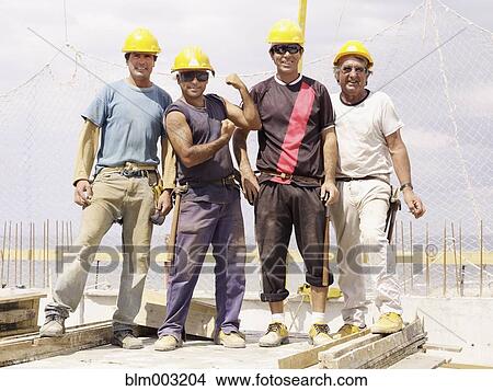 Picture - Hispanic workers standing on construction site. Fotosearch
