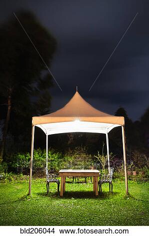 Picture - Illuminated canopy and table in garden. Fotosearch