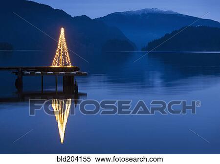 Stock Photography - Illuminated Christmas tree on wooden pier. Fotosearch