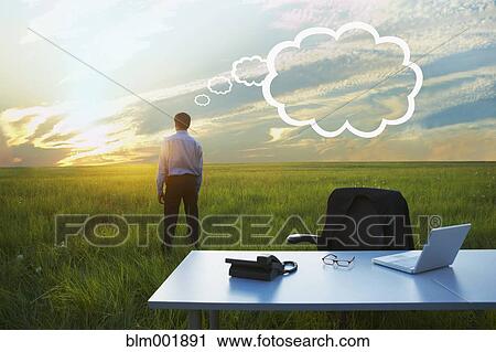 Stock Image - Indian businessman in field with thought bubble. Fotosearch