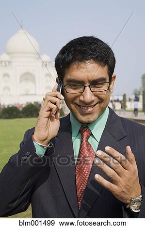 Stock Photo - Indian businessman talking on cell phone at the Taj Mahal. Fotosearch