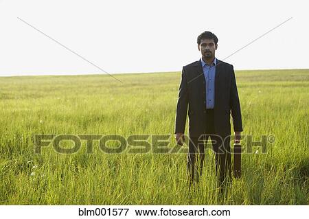 Stock Photo - Indian businessman with briefcase in field. Fotosearch