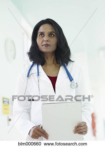 Stock Image - Indian doctor in lab coat holding medical chart. Fotosearch
