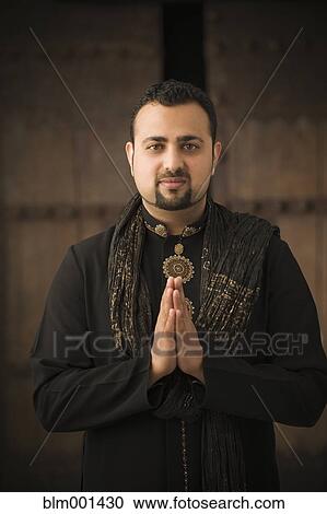 Stock Image - Indian man praying in traditional clothing. Fotosearch