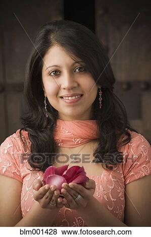 Stock Photo - Indian woman in traditional clothing holding rose petals. Fotosearch