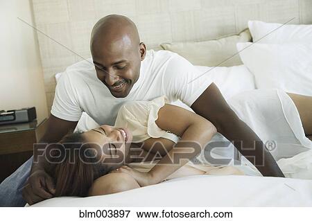 Stock Photo - Intimate couple laying on bed. Fotosearch