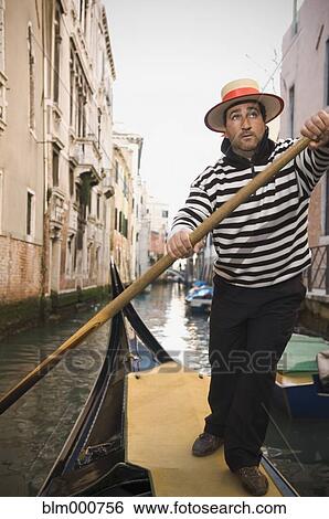 Stock Photograph - Italian gondolier rowing gondola through canal. Fotosearch