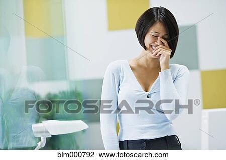 Stock Image - Japanese businesswoman laughing in office. Fotosearch