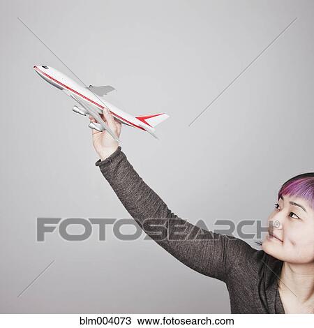 Stock Image - Japanese woman holding toy airplane. Fotosearch
