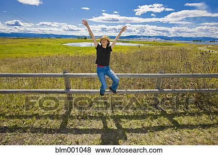 Stock Photo - Japanese woman sitting on remote countryside field. Fotosearch