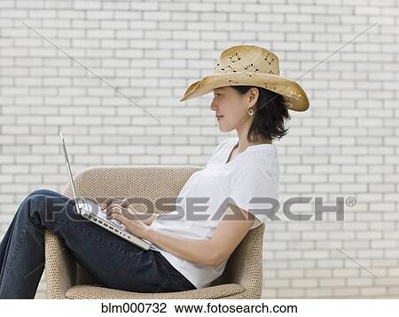 Japanese woman typing on laptop wearing cowboy hat View Large Photo Image Stock Image - Japanese woman typing on laptop wearing cowboy hat. Fotosearch