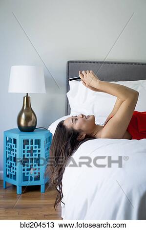 Japanese woman using cell phone on bed View Large Photo Image Stock Image - Japanese woman using cell phone on bed. Fotosearch