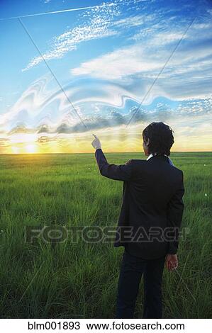 Stock Image - Kazakh businesswoman swirling sky with finger. Fotosearch